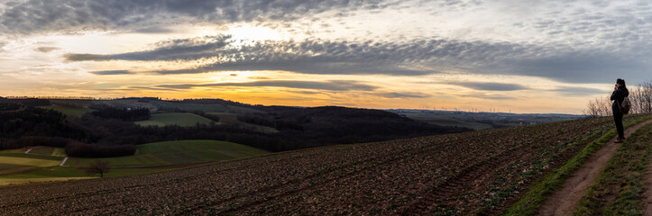 Fototapeta na wymiar Panorama of a sunset over fields in the mountains in Eifel Germany