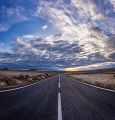 Naklejka premium Carretera en el desierto cielo nublado