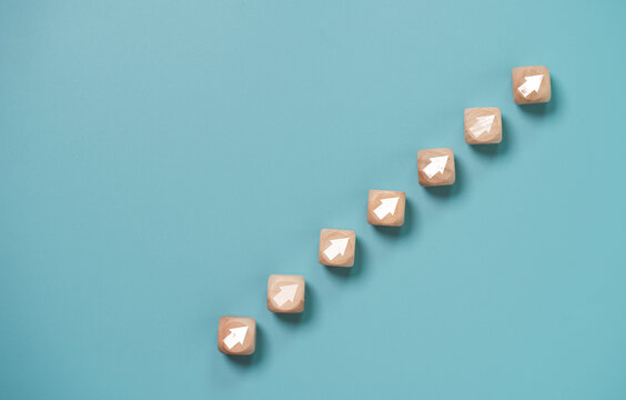 Business investment growth concept , Wooden cube block which print screen up and increase white arrow on blue background.