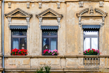 Fototapeta na wymiar Partial view of a weathered but beautiful house front windows with colorful geranium flowers, Saxony, Germany