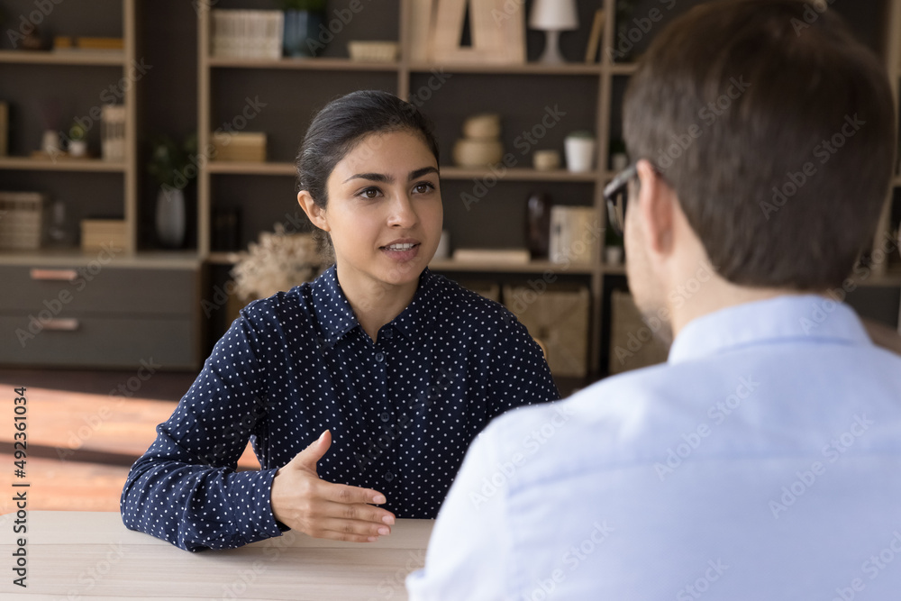 Canvas Prints Confident Indian female meet male business partner investor sit at negotiation table talk discuss commercial deal explain project benefits. Smart young lady tell about herself to hr on job interview