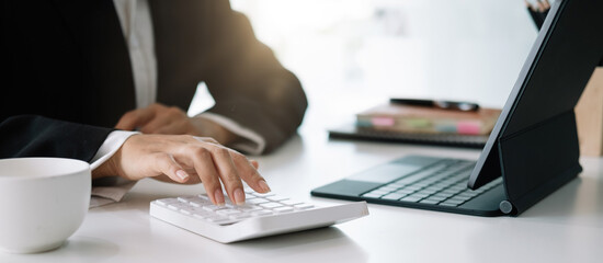 Close up woman planning budget, using calculator and digital tablet, reading documents, young female checking finances, counting bills or taxes, online banking services, sitting at desk