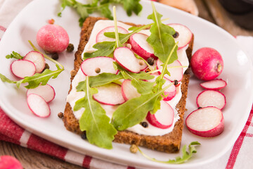 Rye bread with cottage cheese, radish and arugula.
