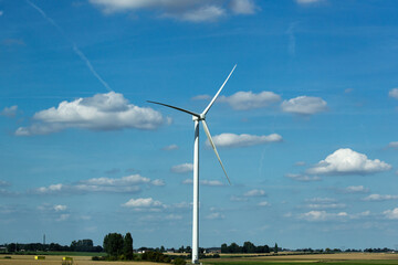 View of wind turbines. White clouds and blues sky. Beautiful summer day..