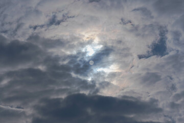 Niebo pokryte ciemnymi, budzącymi grozę chmurami. Spod cienkiej warstwy chmur widać tarczę słoneczną. - 492362264