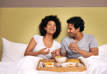 Obraz na płótnie Canvas Breakfast in bed. A cute couple sharing breakfast in bed.