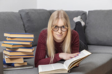 Self education concept. Young woman is lying against the camera and reading a book.