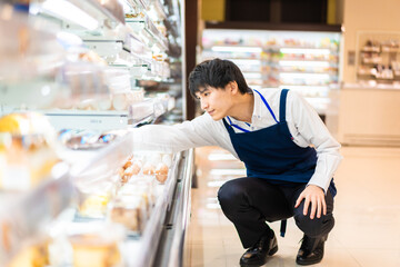 食品スーパーで品出しをする若いスタッフ