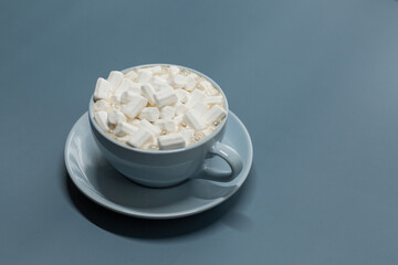 Blue cup of coffee with marshmallows on a blue background