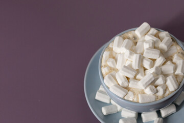 Blue cup of coffee with marshmallows on a purple background