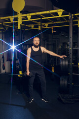 Fototapeta na wymiar A young man with a beard is posing in the gym with dumbbells