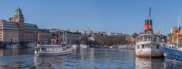  Panorama view at the water front pier with apartment and hotel houses, commuting boats in in the calm water bay Ladugårdsviken a sunny winter day in Stockholm