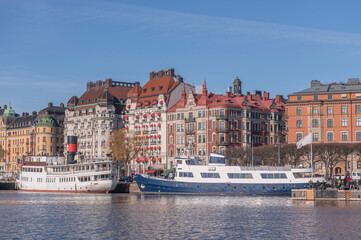 Panorama view at the water front pier with apartment and hotel houses, commuting boats in in the calm water bay Ladugårdsviken a sunny winter day in Stockholm