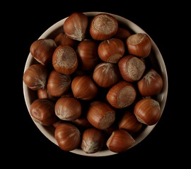 Hazelnuts in bowl isolated on black, top view 