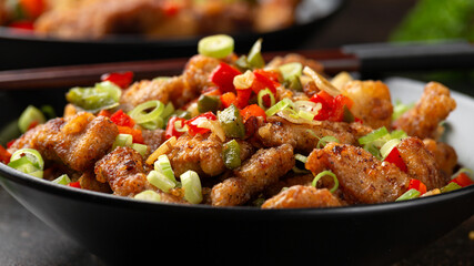 Stir fry salt and pepper pork loin with herbs in black bowl. Asian food
