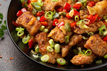 Stir fry salt and pepper pork loin with herbs in black bowl. Asian food
