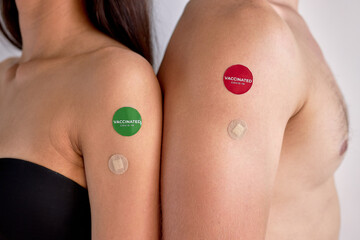 close-up arms of young cropped couple with vaccine after injection isolated on white studio...