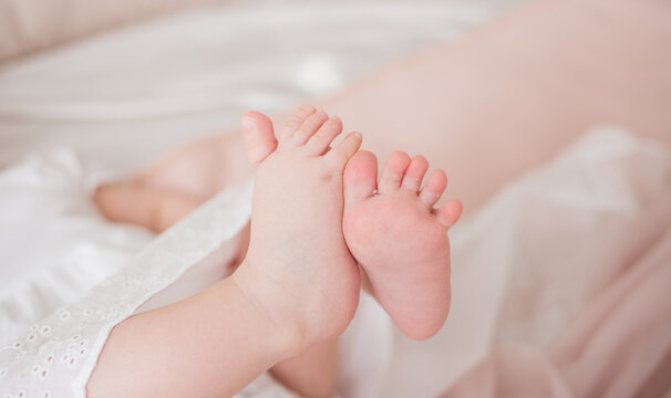 close-up of a child's bare feet on a bed in a room