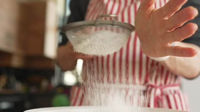 Woman baker sifting flour for dough through bolter