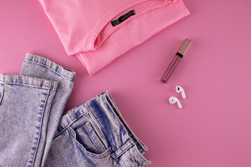 Women's clothing and accessories on a pink background, top view. Modern and casual outfit. Fashion, shopping and makeup concept.