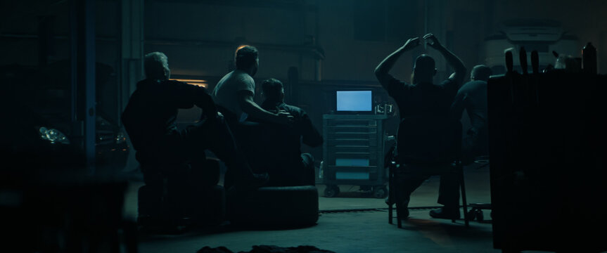 WIDE Car Garage Workshop Workers In Uniforms Watching Portable TV In The Evening, Sport Event