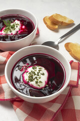 Traditional Ukrainian and Russian national red borscht soup en bol with sour cream and herbs