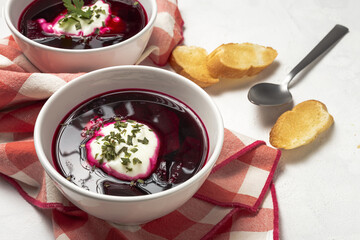 Traditional Ukrainian and Russian national red borscht soup en bol with sour cream and herbs