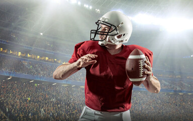 American football sportsman player with ball in action on stadium under lights of background....