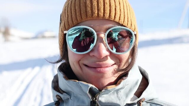 portrait of a woman in sunglasses on the background of winter mountains, a smiling girl on the background of snowdrifts