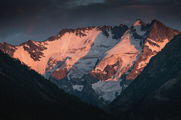 An inspiring landscape with hillsides in the valley and distant mountains covered with snow and glaciers at autumn time