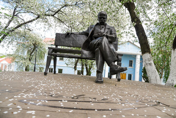 Monument to Taras Shevchenko on a bench in a flowering garden in Kyiv - obrazy, fototapety, plakaty