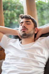 portrait d'un jeune homme de 20 ans qui fait la sieste dans un fauteuil. Il se repose à la maison....