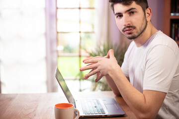 portrait d'un jeune homme souriant de 20 ans qui travaille devant son ordinateur portable à la...
