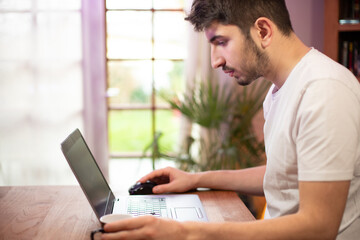 Jeune homme employé de bureau travaille devant son ordinateur portable en buvant un café. Il...