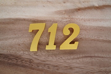Golden Arabic numerals on a real brown and white wooden floor number 712