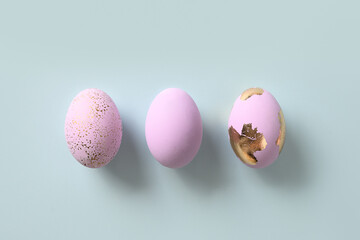Three violet decorative pastel eggs on blue background. Flat lay. Happy Easter greeting card with copy space. Top view.