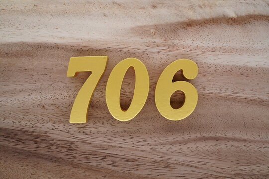 Golden Arabic numerals on a real brown and white wooden floor number 706