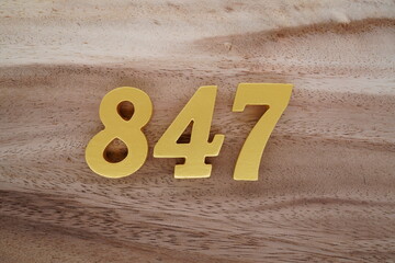 Golden Arabic numerals on a real brown and white wooden floor number 847