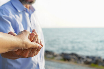 senior asian man hand holding his wife while travelling to the sea,concept elderly...