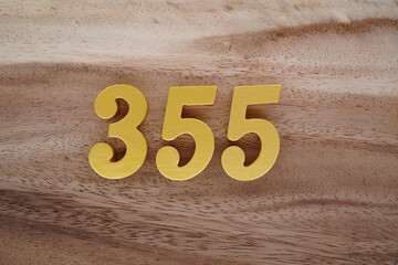 Golden Arabic numerals on a real brown and white wooden floor number 355 