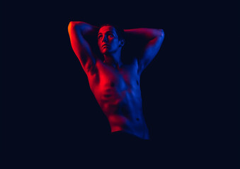 Fashion art photo of a strong young beautiful sexy body of an athlete in red and blue tones of neon light on an isolated dark background in colored spotlights.