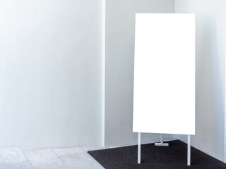 White blank display stand banner on white wall background with copy space. Advertising mockup artboard for pictures or shop information. standing sign template on the ground.