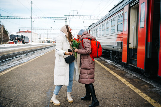 girls with flowers say goodbye on the platform of the station