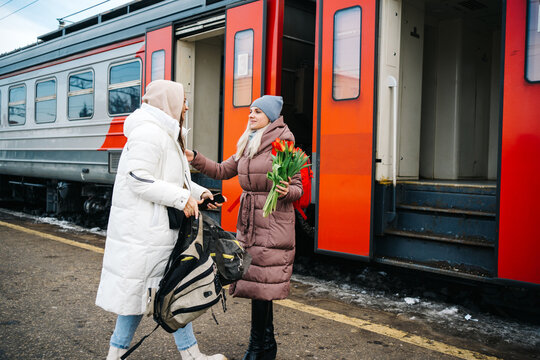 girl escorts a friend to the train, helps carry a bag - Powered by Adobe