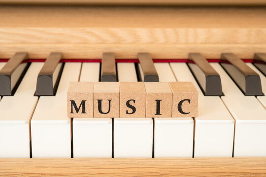 木製ピアノの鍵盤とMUSICの文字