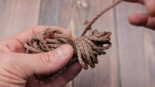 The Coil of rope close-up. Hold the rope. Hands and rope. Brown rope.