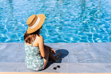 Young woman traveler relaxing and enjoying by a tropical resort pool while traveling for summer vacation, Travel concept