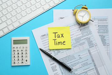 Reminder note with words Tax Time, documents, computer keyboard, calculator and alarm clock on...