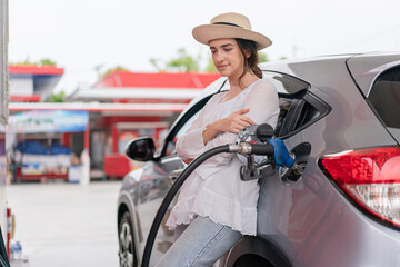 Woman traveler standing and waiting to refuel car self-service in gas station