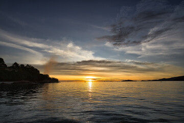 Fototapeta premium Dramatic sunset over sea with clouds in the sky and mountain in background - Thailand Koh Lipe